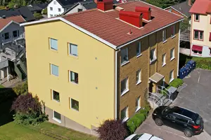 Flerbostadsfastighet med gul fasad, vita fönster och rött tegeltak | Nivika Fastigheter AB (publ)