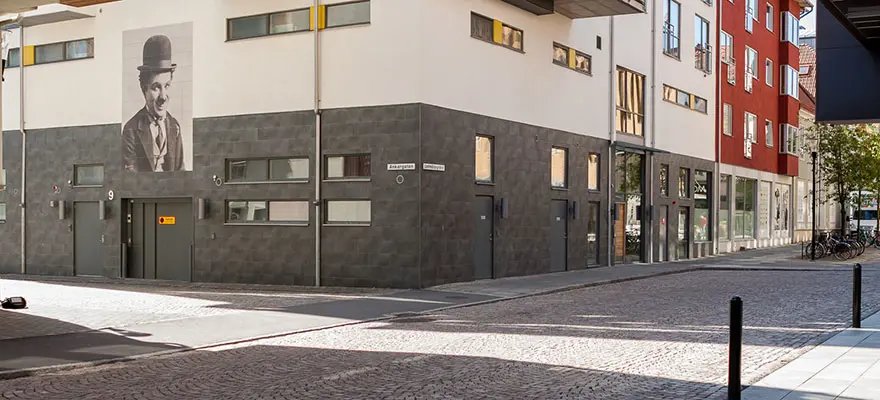 Hörnet på fastigheten med grå och vit fasad, dörrarna och porten är mörkgrå | Nivika Fastigheter AB (publ)