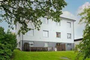 Flerbostadshus med vit fasad, vita fönster och grå husgrund | Nivika Fastigheter AB (publ)