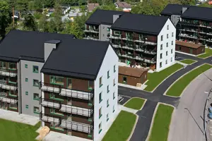 Flerbostadshus med vit, brun och mörkgrå fasad, svart tak | Nivika Fastigheter AB (publ)