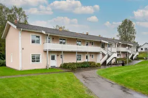 Flerbostadshus med ljusrosa fasad, vita fönster och balkonger | Nivika Fastigheter AB (publ)
