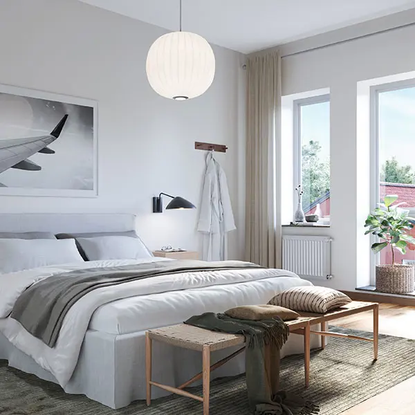 Sovrum med vita väggar, ljust trägolv, matta och en säng | Nivika Fastigheter AB (publ)