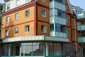 Flerbostadshus med gul tegelfasad, blåa fönster samt balkonger | Nivika Fastigheter AB (publ)