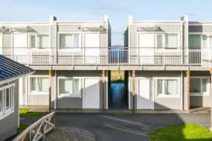 Flerbostadshus med grå fasad, vita fönster samt dörrar | Nivika Fastigheter AB (publ)