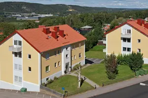 Flerbostadshus med gul och vit fasad, vita fönster och rött tegeltak | Nivika Fastigheter AB (publ)