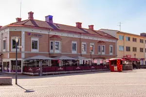 Flerbostadshus med rosa träfasad och vita fönster, kommersiella lokaler på första våningen | Nivika Fastigheter AB (publ)