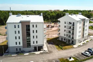 Flerbostadsfastighet med vit fasad samt vitt tak, parkering på framsidan | Nivika Fastigheter AB (publ)