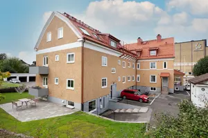 Flerbostadshus med orange tegelfasad, vita fönster, grå balkonger och rött tegeltak | Nivika Fastigheter AB (publ)