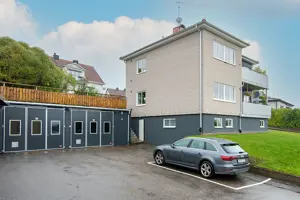 Flerbostadsfastighet med ljus tegelfasad, mörkgrå husgrund samt garage | Nivika Fastigheter AB (publ)