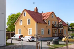 Flerbostadshus med orange potsad fasad, vita fönster och rött tegeltak | Nivika Fastigheter AB (publ)