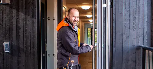 En glad man som håller upp en dörr | Nivika Fastigheter AB (publ)