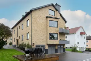 Flerbostadshus med gul tegelfasad, mörkgråa fönster, balkonger och portar | Nivika Fastigheter AB (publ)