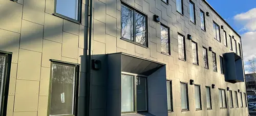 Fastighet med grå fasad och många fönster, närbild | Nivika Fastigheter AB (publ)