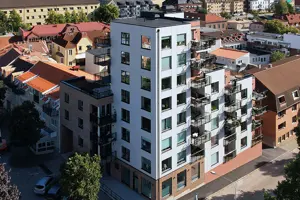 Flerbostadshus med vit och orange fasad, svart och rött tak | Nivika Fastigheter AB (publ)